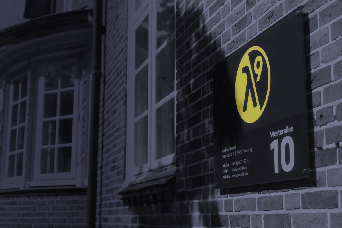 A sign with the lambda9 logo and company address is mounted on a wall.